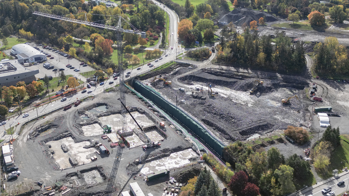 An aerial view in fall of the construction site where the parking garage for The Ottawa Hospital’s new campus is being built. A large tower crane is on site and parts of the concrete foundation have been poured at ground level.