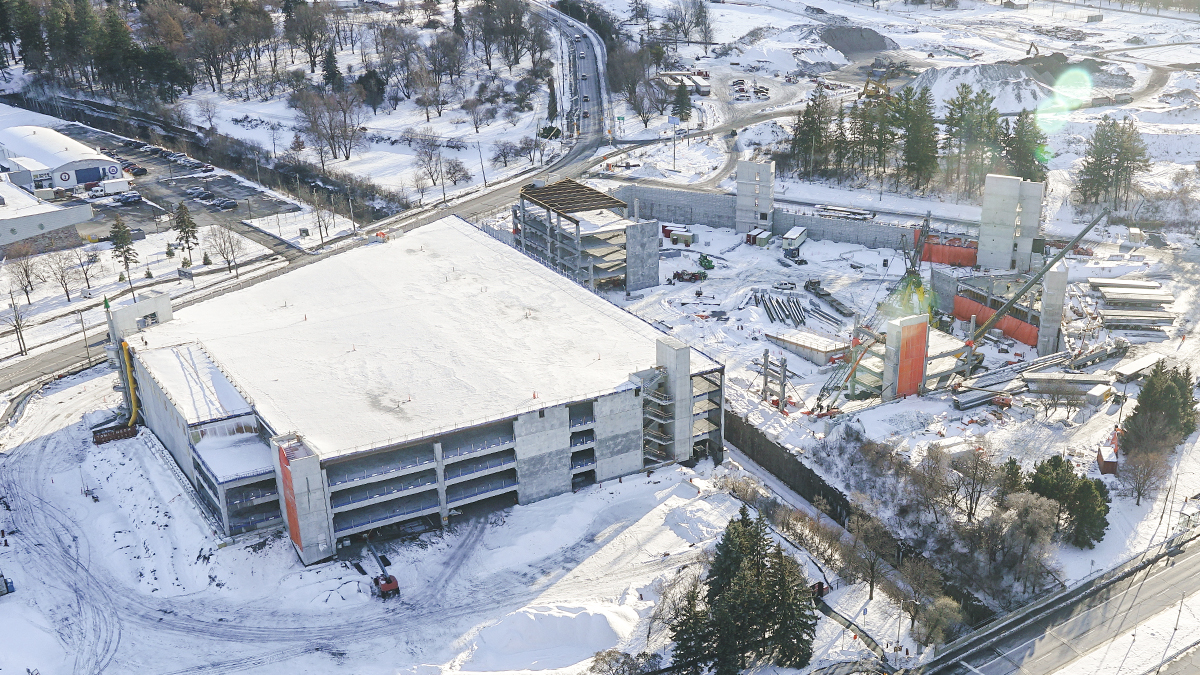 An aerial view in winter of the partially constructed parking garage at The Ottawa Hospital’s new campus. One half of the parking garage is completed and covered by snow, the early stages of construction have begun on the other half.