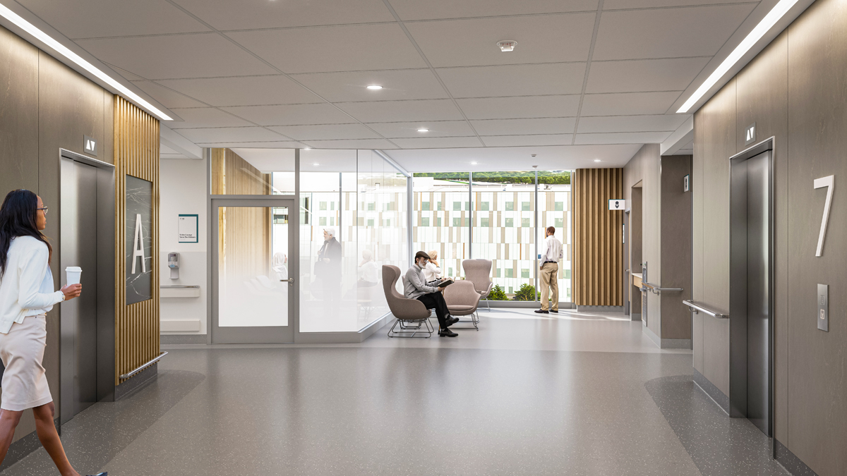 An artist rendering of a hallway inside a new hospital. The hall runs up the middle from the foreground to the background. Elevators are on either side of the hallways at left and right. In the background, there are chairs and large windows showing a clear view of the outdoors. On the left side of the background, a small room has glass walls which are gradually frosted on the lower half. People are standing and seated in various locations throughout the scene.